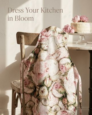 Floral-patterned chair cover draped over a wooden chair with a cake in the background.